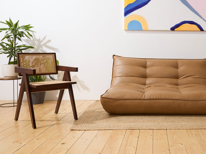 Cane chair and tan sofa with artwork